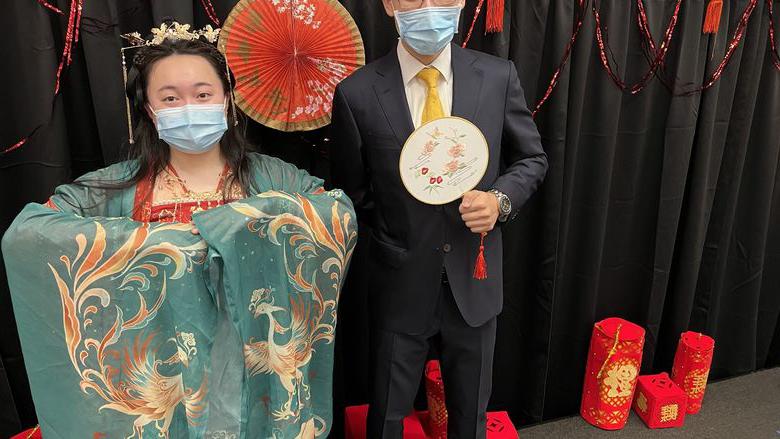 一个男生穿着西装，一个女生穿着中国传统服装.